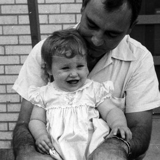 A man holding a laughing young child outdoors.