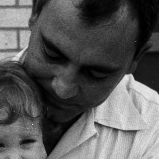 A man holding a laughing young child outdoors.