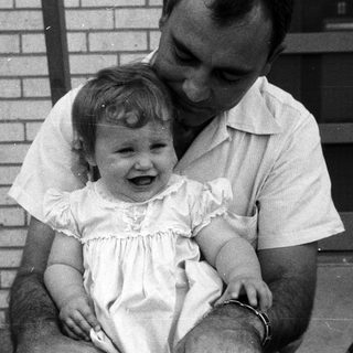 A man holding a laughing young child outdoors.
