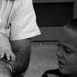 A man holding a laughing young child outdoors.