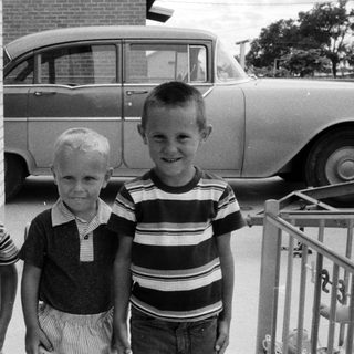 Three boys posing outdoors in 1960s-style clothing.
