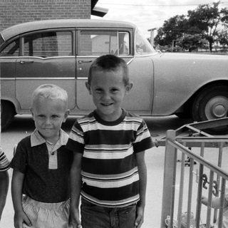 Three boys posing outdoors in 1960s-style clothing.