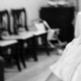 Black-and-white photo of smiling woman in kitchen.