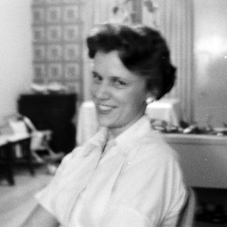 Black-and-white photo of smiling woman in kitchen.