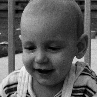Baby laughing while leaning on railing.