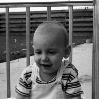 Baby laughing while leaning on railing.