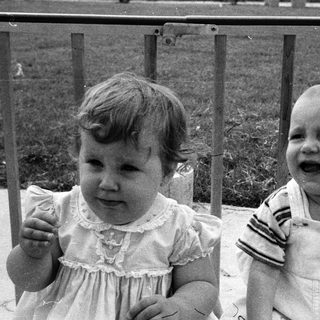 Two young children laughing together outdoors.