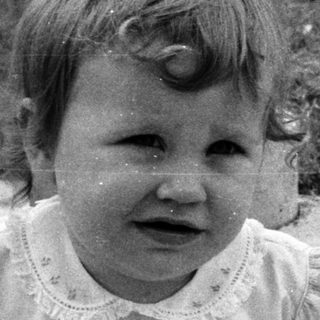 Two young children sitting, one crying, outdoors.