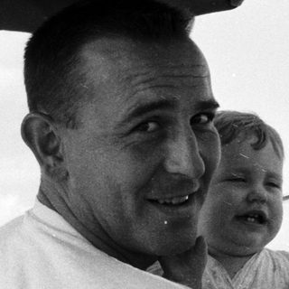 Family in vintage car, man holding baby, smiling.