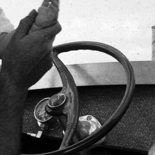 Family in vintage car, man holding baby, smiling.