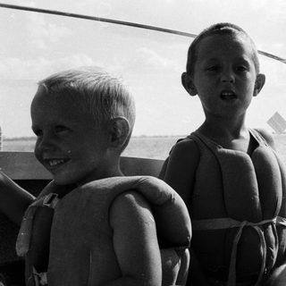 Three people on boat, enjoying water outing.