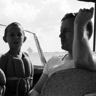 Three people on boat, enjoying water outing.