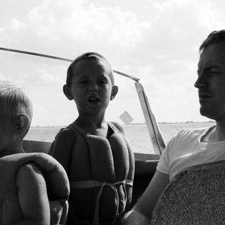 Three people on boat, enjoying water outing.