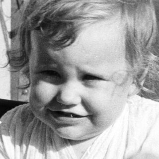Young child laughing happily in a boat seat.