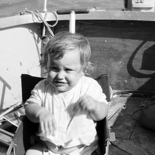 Young child laughing happily in a boat seat.