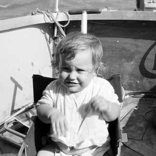 Young child laughing happily in a boat seat.