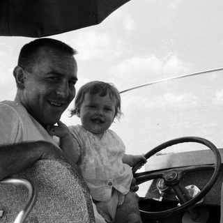 Happy man holding smiling child in vintage car.