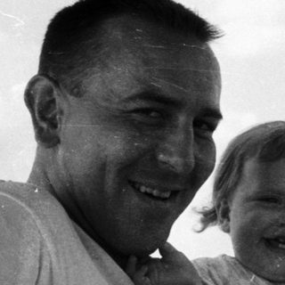 Happy man holding smiling child in vintage car.