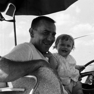 Happy man holding smiling child in vintage car.