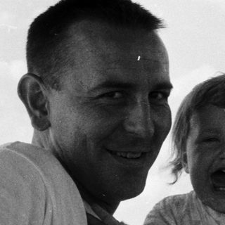 A man and young child laughing in vintage car.