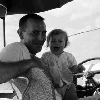 A man and young child laughing in vintage car.