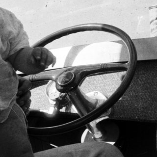 A man and young child laughing in vintage car.