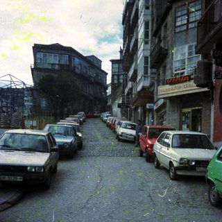 Urban street with parked old cars and aging buildings.