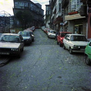 Urban street with parked old cars and aging buildings.
