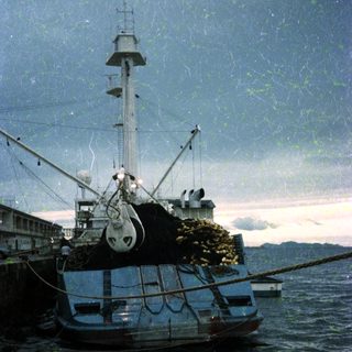 Fishing boat loaded with nets at dock.