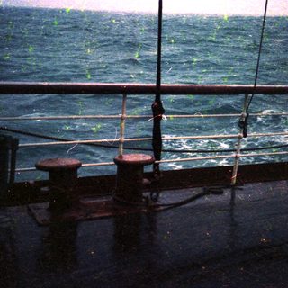 Rusty bollards by stormy sea through rain.