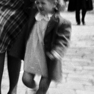 A woman leads a young child along a path.