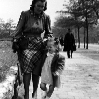 A woman leads a young child along a path.