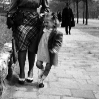 A woman leads a young child along a path.