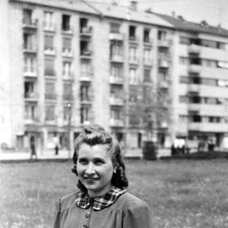 Young woman smiling outdoors in 1940s-style clothing.