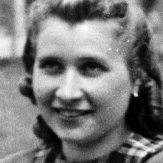 Young woman smiling outdoors in 1940s-style clothing.