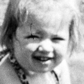 Young child smiling while playing in shallow water outdoors.