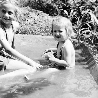 Two children smiling while playing in shallow water.