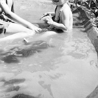Two children smiling while playing in shallow water.