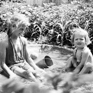 Two children playing in a shallow outdoor pool.