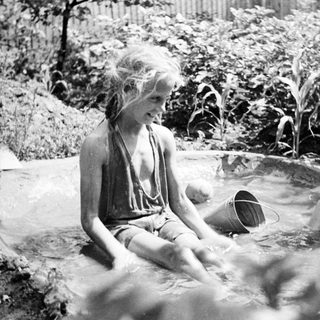 Two children playing in a shallow outdoor pool.