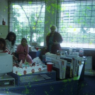 Office group celebrating with cake and drinks.