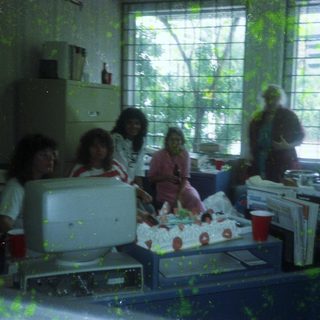 Office group celebrating with cake and drinks.