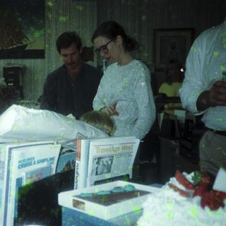 People handling wrapped items in cluttered indoor storage space.