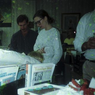 People handling wrapped items in cluttered indoor storage space.