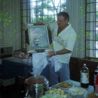 Man holding framed photo in kitchen with food.