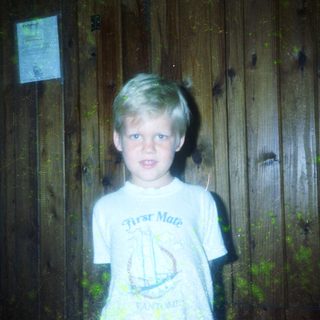 Young boy wearing "First Mate" shirt standing outdoors.