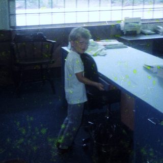 Child standing in messy, painted room.