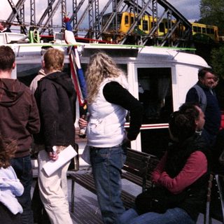Boat tour with passengers near a bridge.