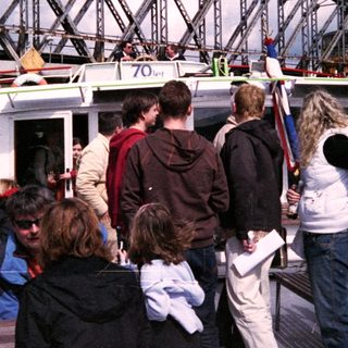 Boat tour with passengers near a bridge.