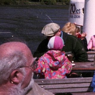 Family enjoying riverboat cruise with scenic mountain views.